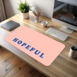 Infidu Hopeful Desk Pad with blue text on a baby pink background, motivational design desk pad kept on the table