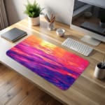 Infidu Calming Sunset Reflection Design Desk Pad featuring a sunset over water in soft shades of pink, purple, orange, and yellow. desk pad kept on the table