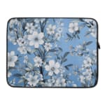 Elegant laptop sleeve with a blue background and white flowers with gray details, featuring small blossoms and leaves, secured with a zip. laptop sleeve kept on a plain white background