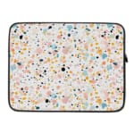 Laptop sleeve with a colorful speckled design in black, orange, blue, and yellow on a light background, featuring a secure zip closure. laptop sleeve kept on a plain white background