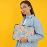 Laptop sleeve with a playful pastel spiral design on a white background. the person holding the sleeve