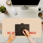 Infidu desk pad with 'Be Awesome Today' in orange text on a beige background, providing a motivational and stylish desk mat. A writing pad on top of the desk pad