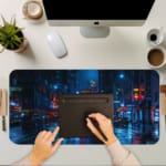 Infidu Neon Lights Midnight City Reflections Desk Pad shows a moody, rainy city scene with neon reflections, perfect for a modern workspace. A writing pad on top of the desk pad