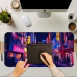 Infidu Neon City Street Desk Pad features a vibrant nighttime city scene with neon lights in pink, purple, yellow, and blue, perfect for any desk setup. A writing pad on top of the desk pad