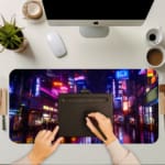 Infidu Neon City Street Desk Pad with a vibrant urban night scene featuring neon lights, tall buildings, and colorful reflections on wet pavement. A writing pad on top of the desk pad