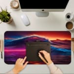 Infidu Vibrant Ocean Wave Design Desk Pad showcases colorful waves in shades of purple, pink, blue, and red against a dramatic sky. A writing pad on top of the desk pad