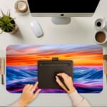 Infidu Serene Sunset Wave Design Desk Pad features colorful soft waves in blue, purple, and pink with a yellow and orange sunset. A writing pad on top of the desk pad