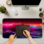 Infidu Neon Ocean Waves Design Desk Pad with vibrant shades of pink, purple, blue, and orange depicting ocean waves and sunset. A writing pad on top of the desk pad