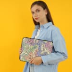 Laptop sleeve with topographic map design in pastel colors, featuring contour lines on a neutral background. the person holding the sleeve