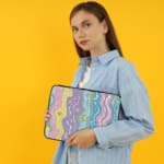 Retro-inspired laptop sleeve with wavy pastel stripes in pink, purple, yellow, green, and blue, covering the surface with a zip closure. the person holding the sleeve