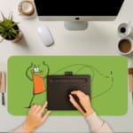 Playful cartoon character desk pad with light green background and minimalistic design featuring a cheerful character in an orange shirt. A writing pad on top of the desk pad